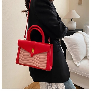 Detail of red and pink wavy quilted leather handbag with gold metal clasp on a model
