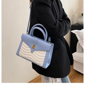 Side view of large crocodile texture handbag with wave quilting and metal swivel lock