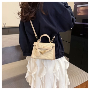 Detail of woven straw mini bag with beige leather trim and golden clasp on a model