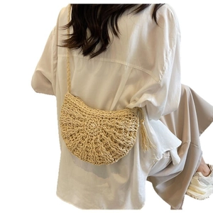 Handwoven straw half-moon crossbody bag with decorative side tassels and slim strap