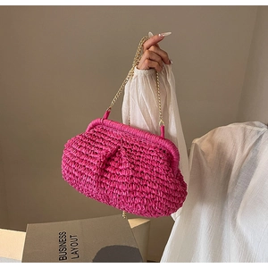 Détail du sac en raphia tressé fuchsia avec fine bandoulière en chaîne dorée