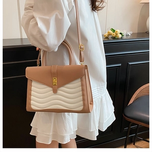 Close-up of wavy quilted pattern on brown and cream leather crossbody bag with gold lock