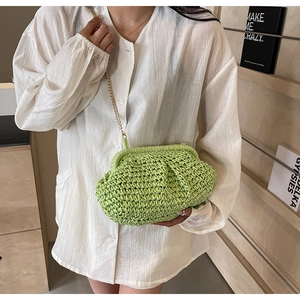 Détail du sac tressé vert avec bandoulière chaîne dorée porté sur chemise blanche