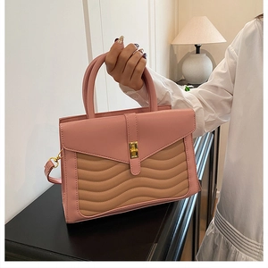 Detail of pink and khaki crossbody bag with quilted wave pattern and gold metal clasp