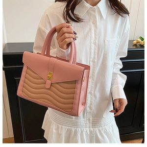 Detailed view of pink and tan bag with wave stitching and golden square lock