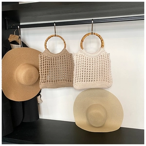Detail of hollow-out knit beach bags with natural bamboo handles in khaki and beige