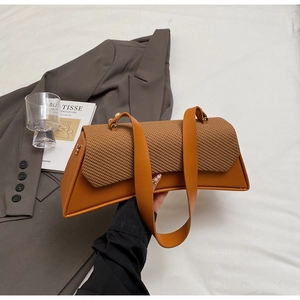 Detail of caramel shoulder bag featuring a woven flap and elegant curved silhouette