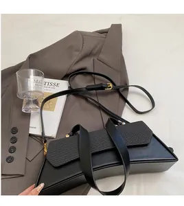 Detail of adjustable long shoulder strap and gold hardware on black crossbody bag
