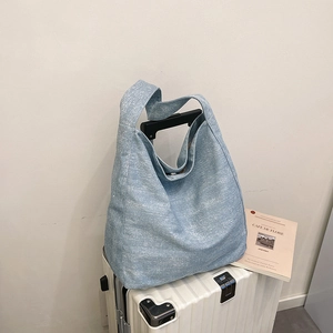 Light blue canvas hobo bag with large capacity hanging on a suitcase in a cafe setting