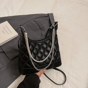 Elegant black quilted hobo handbag with metal chains and pearl accent on a grey blazer