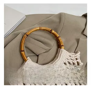 Detailed shot of a beige hollow knit bag with a round natural bamboo handle texture