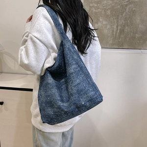 Sparkly dark blue denim tote bag with glitter accents shown in a stylish shoulder carry view
