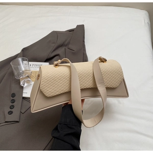 Detail of a contrast weave and leather crossbody bag with gold lock on a grey suit jacket