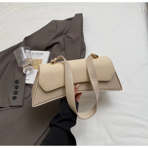 Detail of woven texture flap and smooth beige synthetic leather on trapezoid shoulder bag