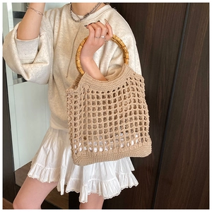 Detail of the woven hollow net bag with round natural bamboo handles for beach use