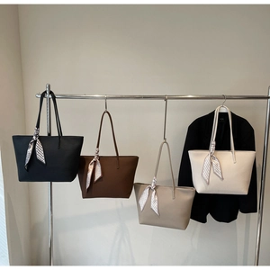 Detail of multi-color lychee texture tote bags with geometric silk scarves on metal rack