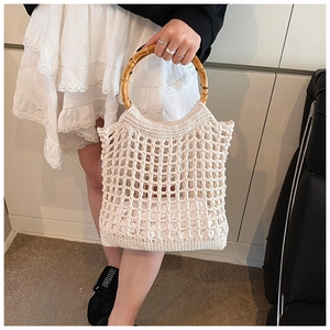 Detail of hollow knit beach bag featuring natural bamboo handles and internal pouch