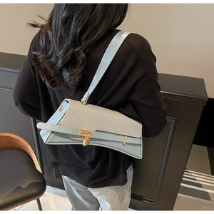 Detail of light blue and beige patchwork shoulder bag with golden lock and curved base