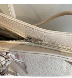 Detail of silver zipper closure on beige lychee leather tote bag with silk scarf