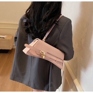 Pink triangular shoulder bag on model featuring golden padlock and textured leather