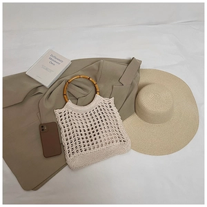 Detail of hollow-out knit bag with a distinct bamboo ring handle and beige mesh pattern
