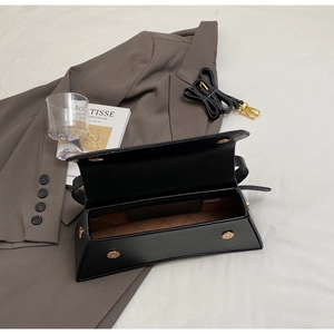 Detail view of the black crossbody bag showing its interior lining and gold magnetic closure