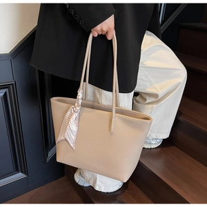 Detail of beige lychee grain leather tote bag with a pink plaid scarf on the handle