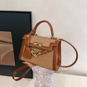 Straw and brown leather Kelly bag with golden turn-lock shown in an artistic lifestyle setting