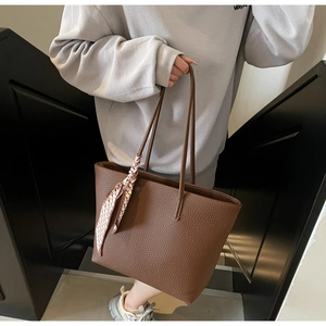 Detail of brown litchi pattern leather tote bag with decorative silk scarf on handle