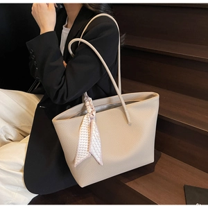 Minimalist apricot tote bag with heart-pattern scarf on black blazer and wooden stairs