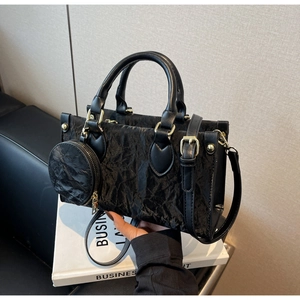 Detail of black pleated texture bag with round coin purse and golden hardware accents