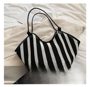 Detail showing the black and white striped woven texture and thin shoulder straps of the tote