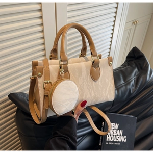 Detail of off-white marble pattern handbag with brown leather handles and small round charm
