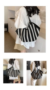 Detail of a large woven tote bag with black and white vertical stripes and leather straps