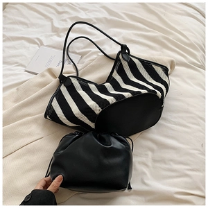 Close-up of black and white striped woven tote bag with a drawstring inner pouch on white bedding