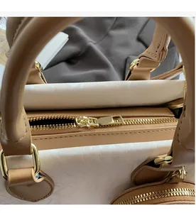 Close-up of smooth gold metal zipper and light brown leather trim on crossbody bag