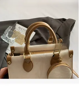 Detailed close-up of cream and brown crossbody bag with circular charm and metal buckle