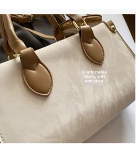 Detail of beige marble pattern fabric and brown leather handle with gold hardware