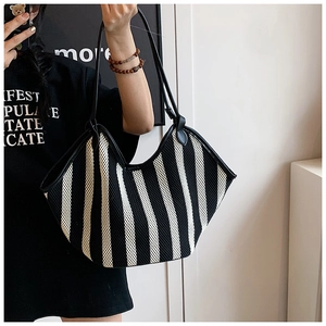 Detail of hand-held black and white striped woven tote bag with slim leather straps