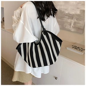 Close-up of black and white striped knit tote bag with black leather shoulder strap