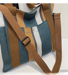 Close-up of striped canvas tote fabric texture and adjustable brown shoulder strap details