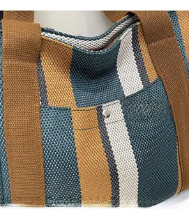 Detailed texture of striped woven tote bag with brown fabric handles and metal rivet