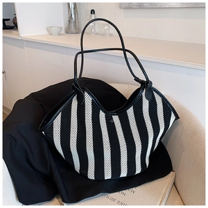 Detail view of black and white striped knit tote bag with slender leather handles on a chair