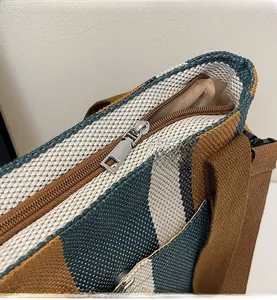 Detail of smooth metal zipper closure on multi-color woven tote bag with vertical stripes