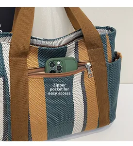 Detail of outer zipper pocket on striped woven tote bag showing easy phone access