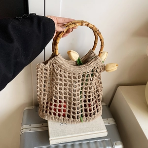 Hollow knit beach bag with bamboo handles on silver suitcase for summer travel