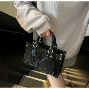 Detail of black tote bag with wrinkled texture, gold hardware and round coin purse pouch