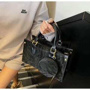 Detail of black pleated shoulder bag with gold hardware and matching round coin pouch