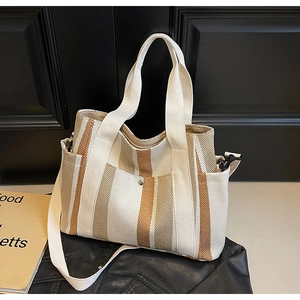 Close-up of canvas tote bag with brown vertical stripes and metal snap button pocket