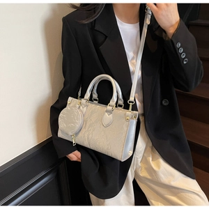Detail of silver textured handbag with round coin purse and detachable shoulder strap